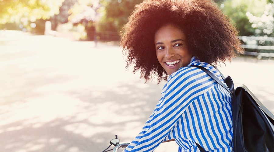 Une étudiante roule à vélo et porte un sac à dos